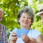 2 older men and a woman playing cards