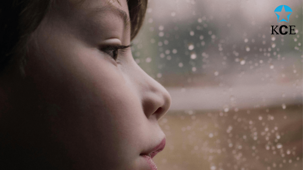 Young person looking out the rain soaked window sadly their game has been cancelled.